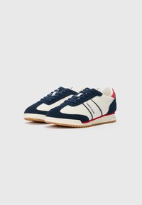 Adidași albi și albastri marin, cu talpă din gumă, accente roșii și logo-ul "Tommy Jeans" pe lateral.