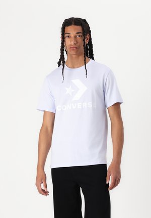 Tricou din bumbac de culoare violet deschis, cu un logo alb Converse proeminent, având design cu stea și săgeată. Mâneci scurte și decolteu rotund.