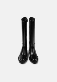 Černé kožené boty ke kolenům s hladkým povrchem, zaoblenou špičkou a bočním zipem pro snadné obouvání. Plochá gumová podrážka.