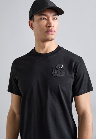 Zwarte katoenen t-shirt met korte mouwen, voorzien van een gestructureerde slangengrafiek op de borst. Het shirt heeft een ronde halslijn en een fitted stijl.