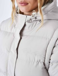 Lys grå pufferjakke med høj krave, der har et broderet logo. Glat, quiltet tekstur og justerbar snøre i hætten.