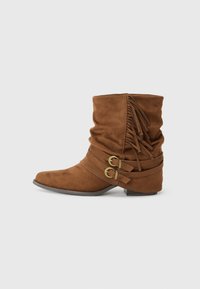Brown suede ankle boots with a slouchy design, featuring two decorative straps with gold-tone buckles and fringe details at the back.