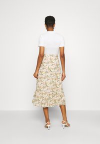 Kukkakuosinen midimekko, jossa on istuva valkoinen yläosa ja teksturoitu bodi. Mekossa on levenevä röyhelöhame pastellisävyissä ja kukkakuosilla.