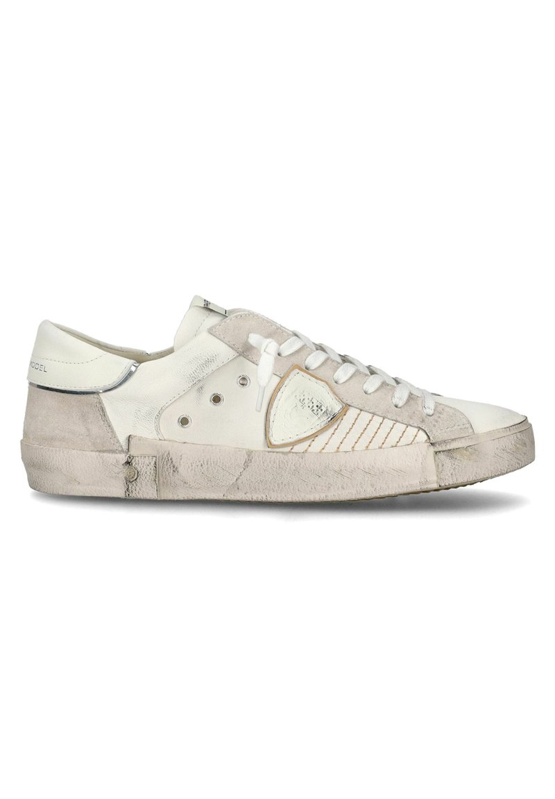 Sneaker bianco con dettagli in suede, pannello laterale testurizzato e particolari metallici argento. Presenta lacci bianchi e una suola in gomma leggermente usurata.