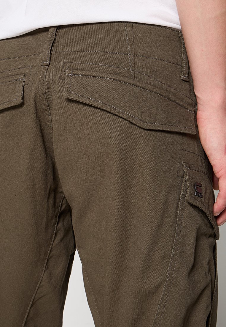 Pantalones cargo marrones con corte recto, múltiples bolsillos, tela resistente y detalles de costura en contraste. Logotipo de parche en el bolsillo.