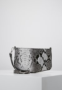 Clutch in schwarz-weißem Kunstschlangenleder, mit glatter Textur und abnehmbarem Tragegurt, in rechteckiger Form und mit subtilen Mustern.