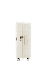 Valise à roulettes rigide de couleur blanc cassé avec texture striée, fermeture éclair rose gold et roues doubles pour une grande mobilité. Elle dispose d'une poignée latérale et d'un verrou.