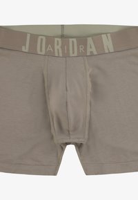 Caleçons boxers marron clair avec une poche de soutien, dotés d'une ceinture élastique beige avec "JORDAN" imprimé en lettres majuscules.