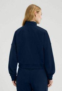 Felpa cropped blu navy con collo alto, maniche oversized e orlo a coste, realizzata in morbido tessuto dalla superficie liscia.