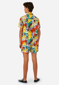 Ensemble de chemise à manches courtes et de shorts colorés avec un graphique Pikachu vibrant, des motifs mélangés et des designs géométriques audacieux en bleu, rouge et jaune.