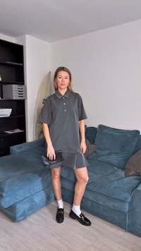 Robe grise à manches courtes avec un col et une rangée de boutons, associée à des mocassins noirs et une pochette, le tout sur un canapé turquoise.