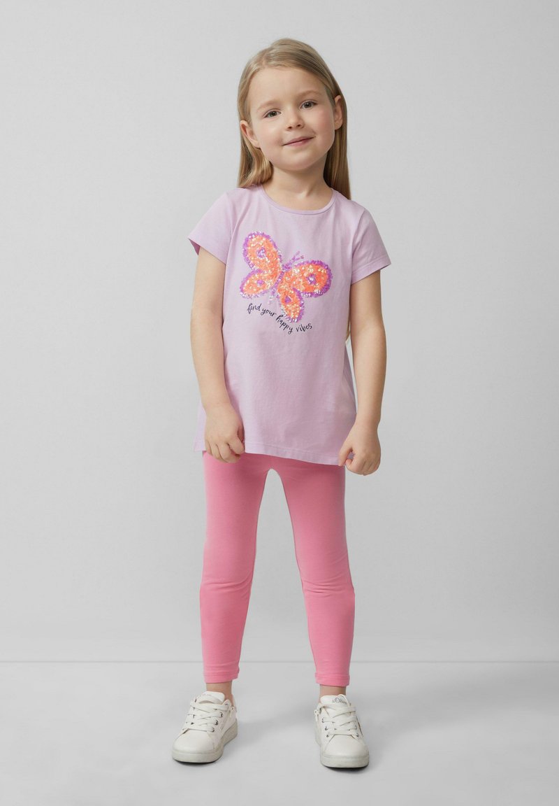 Roze t-shirt met korte mouwen, voorzien van een meerkleurig paillettenvlinderontwerp en de tekst "vind je blije vibes", gecombineerd met roze leggings.