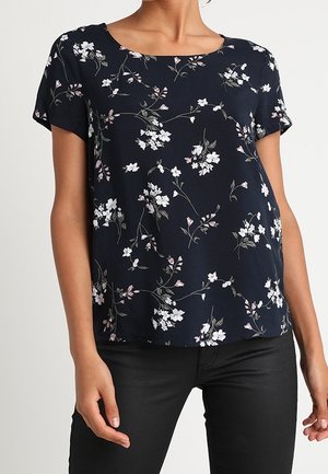 Blouse marine à manches courtes, avec un motif floral blanc et rose. Tissu lisse et encolure carrée ; coupe décontractée.