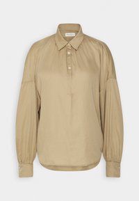 Chemise beige à manches longues avec col à boutons, patte de boutonnage à l'avant et épaules froncées ; confectionnée en tissu léger et lisse.