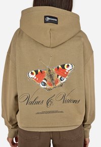 Khakifarbener Kapuzenpulli mit einem großen, bunten Schmetterlingsmotiv auf der Rückseite und dem Text "Werte & Visionen" darunter. Weicher Stoff, lockere Passform.