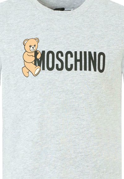 T-shirt en coton gris avec un graphique de cartoon d'ours et le texte "MOSCHINO" en lettres noires en gras en dessous. Design à col rond.