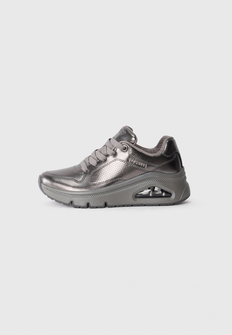 Chaussure de sport gris métallique avec une surface texturée, un bout rond, un système de laçage, un collier rembourré et un amorti d'air visible dans la semelle.