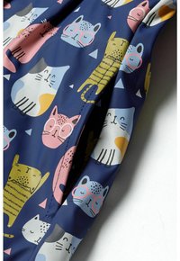 Tissu bleu marine présentant des illustrations colorées de chats dans diverses poses et expressions, avec des motifs triangulaires et circulaires en accents.