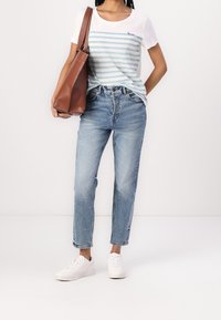 Conjunto casual que incluye una camisa blanca con rayas azules y detalle de "amor", jeans azul claros y zapatillas blancas. Incluida una bolsa tote marrón.