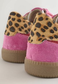 Rosa Wildlederschuhe mit einem Akzent aus Leopardenfell an der Ferse. Gummisohle mit strukturiertem Finish. Nahaufnahme zeigt die Designdetails.