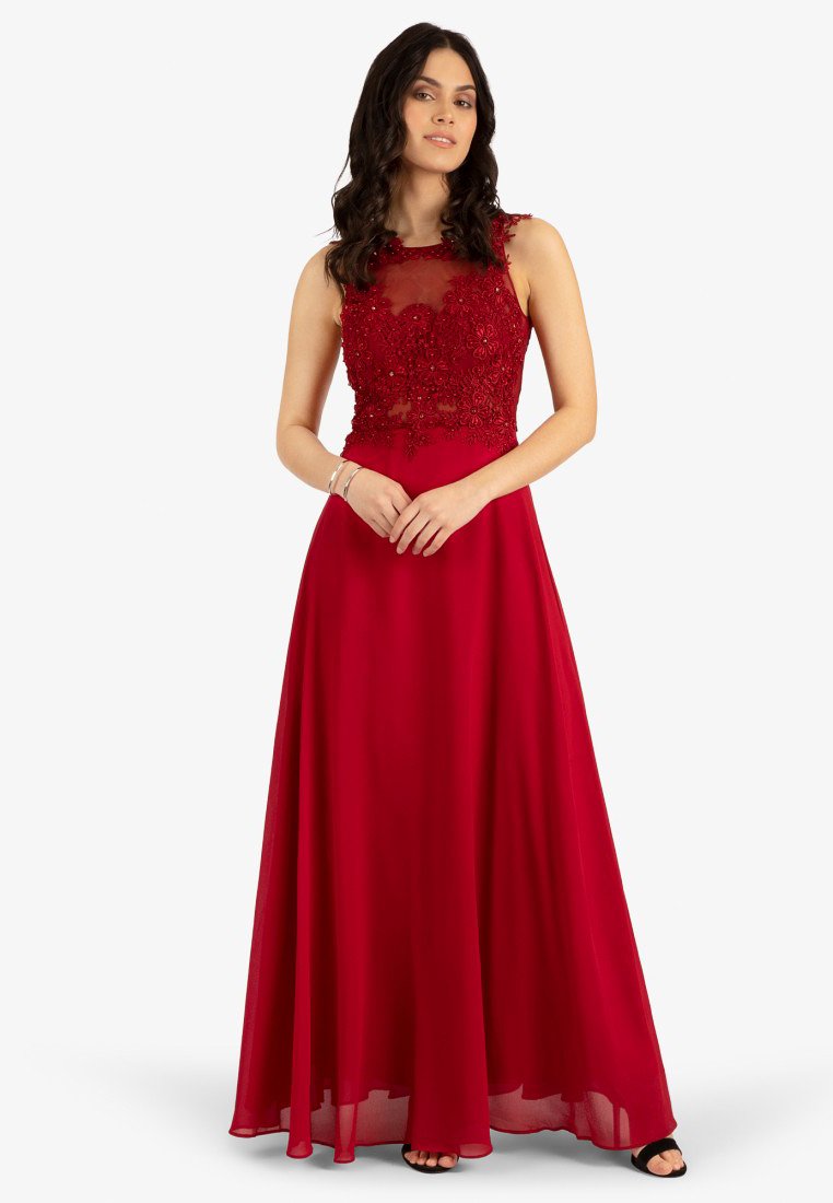 Rotes Kleid mit einem durchsichtigen, verzierten Oberteil, das mit floralen Perlen besetzt ist; fließender Rock aus leichtem Stoff; ärmelloses Design.