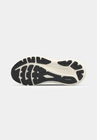 Semelle de chaussure avec une bande de roulement en caoutchouc noir et blanc présentant des motifs de grip texturés pour l’adhérence et la durabilité sur un fond gris clair.