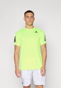 Camiseta deportiva de color verde neón con mangas cortas, presenta detalles y logotipo en negro, fabricada con un tejido ligero y transpirable.