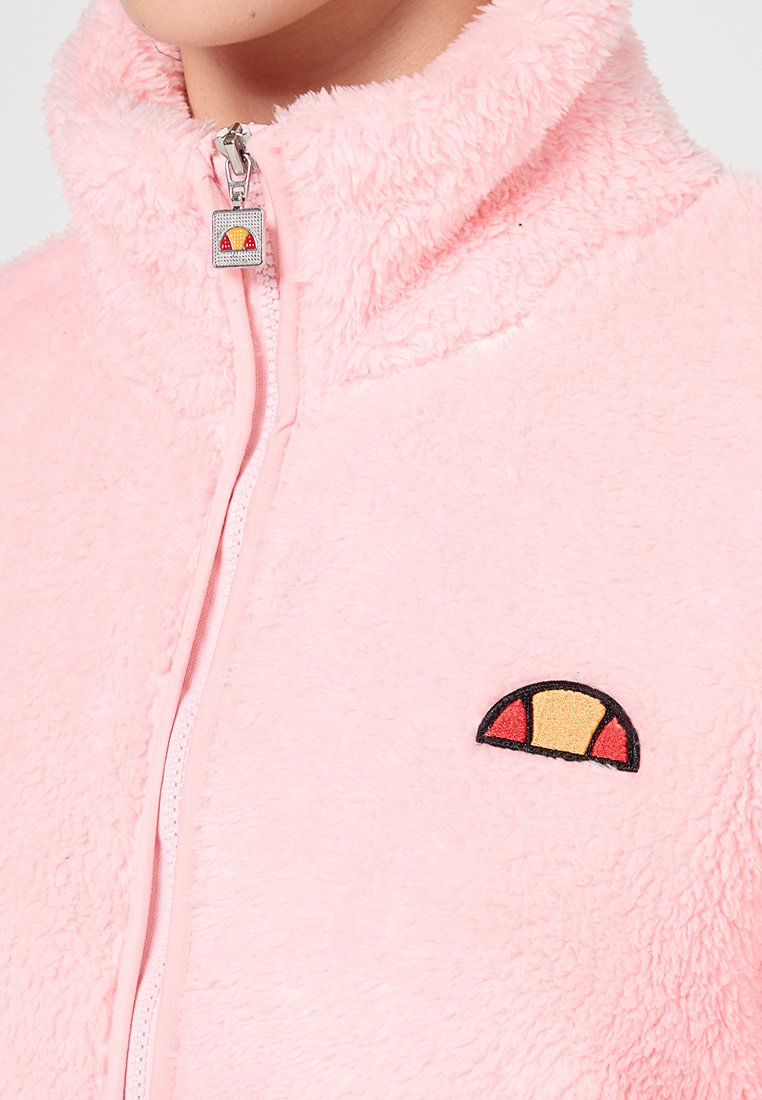 Rosa Fleecejacke mit hohem Kragen, Frontreißverschluss und besticktem Logo mit roten, gelben und schwarzen Akzenten auf der Brust.