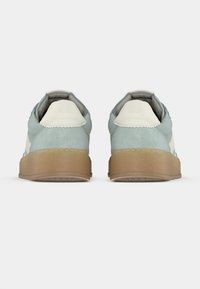 Ζευγάρι αθλητικά παπούτσια σε ανοιχτό γαλάζιο και λευκό με σόλες από καουτσούκ, που φαίνονται από πίσω πάνω σε απλό λευκό φόντο.