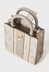 Lille beige og creme farvet håndtaske med to runde håndtag, lodrette striber og et guldfarvet Guess-logo på forsiden.