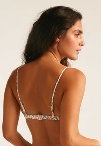 Top de bikini multicolor con tirantes delgados ajustables y cierre de clip. Presenta un patrón floral en suaves tonos pastel.