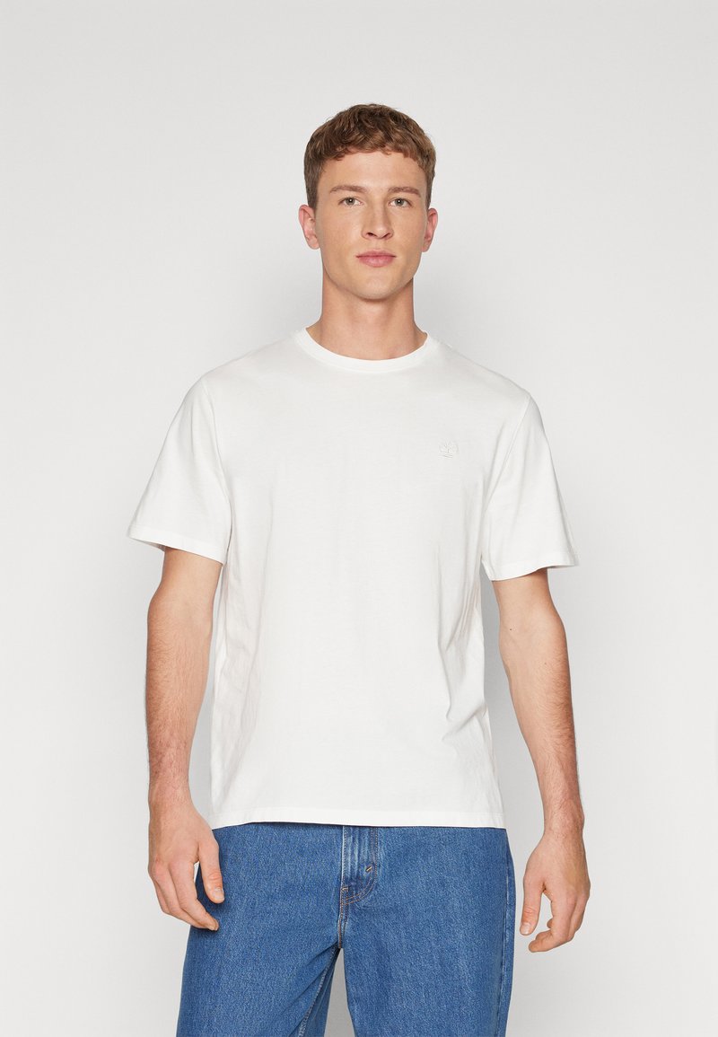 Tricou alb din bumbac, cu mânecă scurtă, decolteu rotund și un logo subtil pe piept, asortat cu blugi din denim albastru.