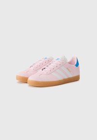 Rosa mockaskinnsneakers med vita ränder, sula i gummirubber och blå hälaccent. Har snörning och texturerad ovandela.