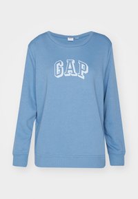 Sudadera azul de manga larga con "GAP" en letras blancas en el pecho, confeccionada en suave algodón y con puños acanalados.