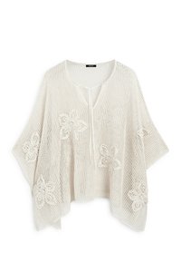 Luźny biały poncho z siateczki z haftami kwiatowymi i zapięciem na kokardkę z przodu, zaprojektowane do lekkiego warstwowego noszenia.