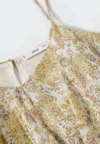 Robe blanche à motifs floraux avec des détails dorés et des touches de violet. Comprend des bretelles fines et un dos à trou en forme de clé. Étiquette visible au niveau de l'encolure.