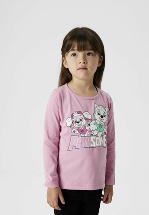 T-shirt à manches longues rose clair avec des personnages de chien de dessin animé et le texte "PAWESOME" en lettres majuscules. Tissu doux, encolure ronde.