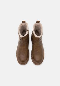 Brązowe botki za kostkę o teksturowanej skórze, z ciepłym podszyciem z sztucznego futra i gumową podeszwą z wzorzystym bieżnikiem zapewniającym przyczepność.