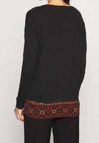 Schwarzer Sweatshirt mit lockerem Schnitt, ausgestattet mit einem bunten, gestickten Saum in roten, orangefarbenen und gelben Blumenmustern.