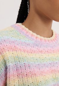Pull rayé pastel en tissu texturé, avec un large col rond et une surface douce et pelucheuse aux tons roses, jaunes et bleus.