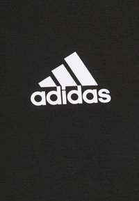 Tissu noir à texture lisse présentant un logo Adidas blanc, composé de trois bandes diagonales et du mot « adidas » en dessous.