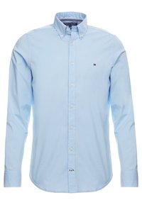 Camisa de botones de manga larga color azul claro, hecha de algodón, con un cuello estructurado y un pequeño logo bordado en el pecho.