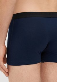Marineblaue Boxershorts mit elastischem schwarzen Bund, aus glattem Stoff, mit taillierter Passform und flachnähenden Nähten.