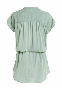 Blouse à manches courtes vert menthe avec un design à dos froncé, un col rond et une coupe décontractée qui tombe doucement. Accents de couture remarquables présents.