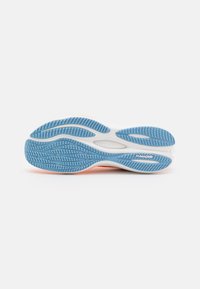 Suela de zapatilla deportiva con un patrón de tracción de goma azul y una entresuela blanca. Presenta canales curvados para flexibilidad y la marca "PUMAGRIP".