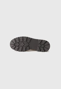 Talpa de cizme din cauciuc cu un profil adânc pentru aderență. Prezintă motive în formă de floare și striații. Culoarea este predominant neagră, cu o suprafață texturată.