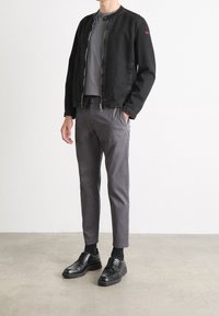 Svart denimjacka med ståkrage, grå T-shirt och grå byxor. Svarta snörskor med texturerad sula. Minimalistisk design.