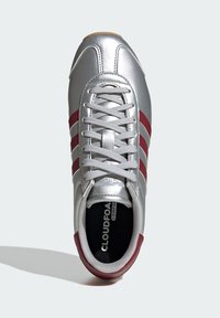 Silver athletic shoe with three red stripes, lace-up design, and textured upper. Includes black insole labeled "CLOUDFOAM." Rubber outsole.