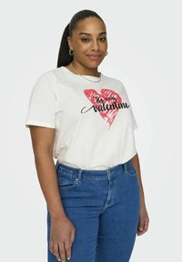 Tricou alb cu un grafic de inimă roșie și text negru "Fii Valentine-ul meu". Asortat cu blugi din denim albastru. Design simplu, cu mâneci scurte.
