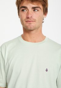 Lys gr�øn bomulds t-shirt med korte ærmer. Har et lille lilla logo på venstre bryst. Blød tekstur med et klassisk rund hals design.